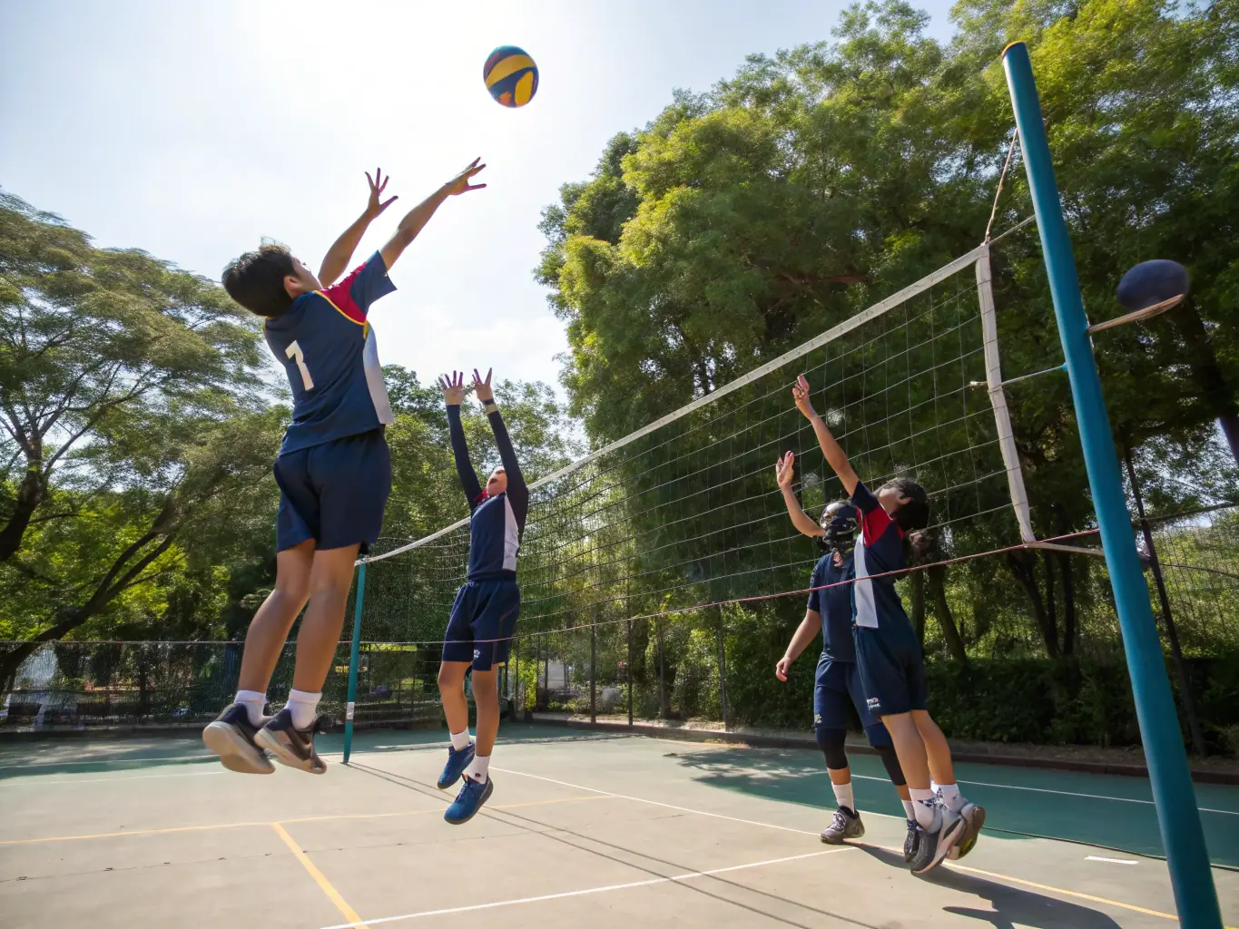 A group of students practicing volleyball in an outdoor setting, emphasizing the coordination and communication involved in the sport.